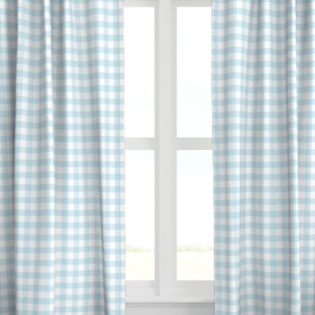 A set of blue drapery panels with a checkered pattern, hanging on a window.