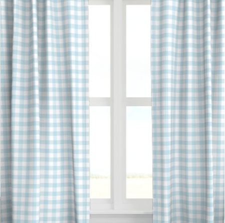 A set of blue drapery panels with a checkered pattern, hanging on a window.