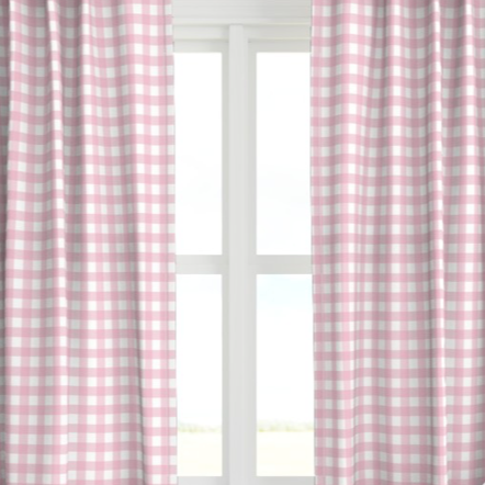 A pair of pink checkered drapery panels hanging on a window, with the light from the window illuminating the room.