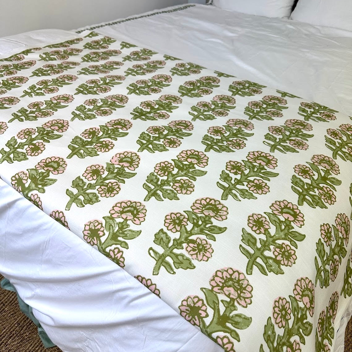 Floral patterned bed footer in pink and green on a bed with white bedding