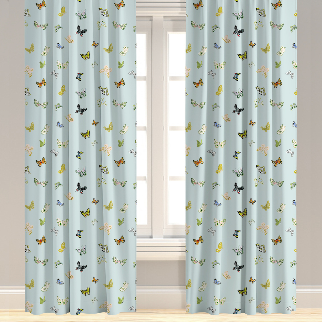 A pair of blue drapery panels with a butterfly pattern, installed on a window.