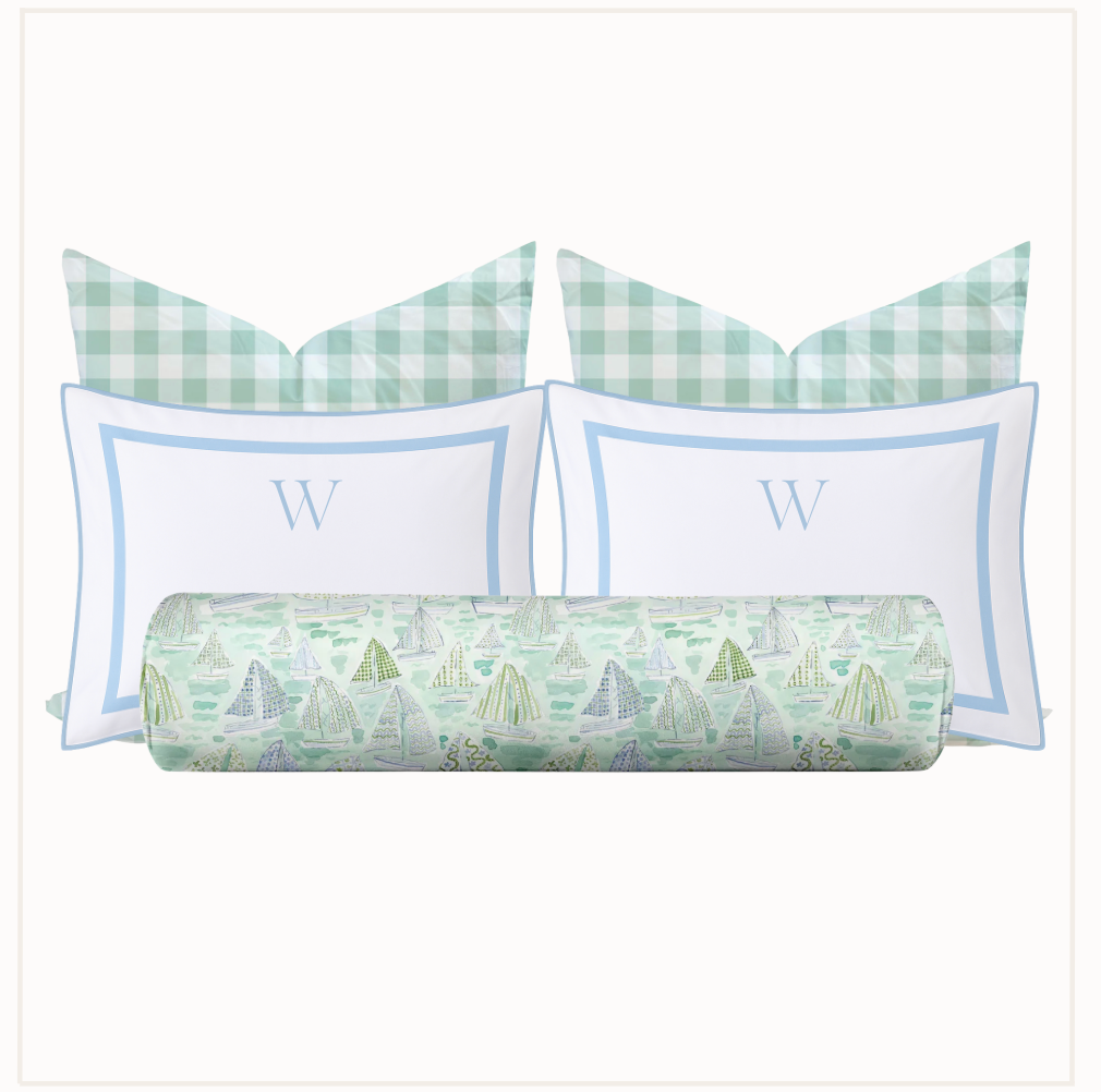 Set of pillows with green and white checkered patterns and a cylindrical pillow with sailboat design on a white background.