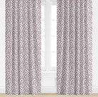 Pair of purple patterned curtains on a window with a white background