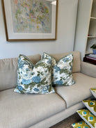 Beige sofa with floral-patterned cushions next to a framed picture on a white wall.