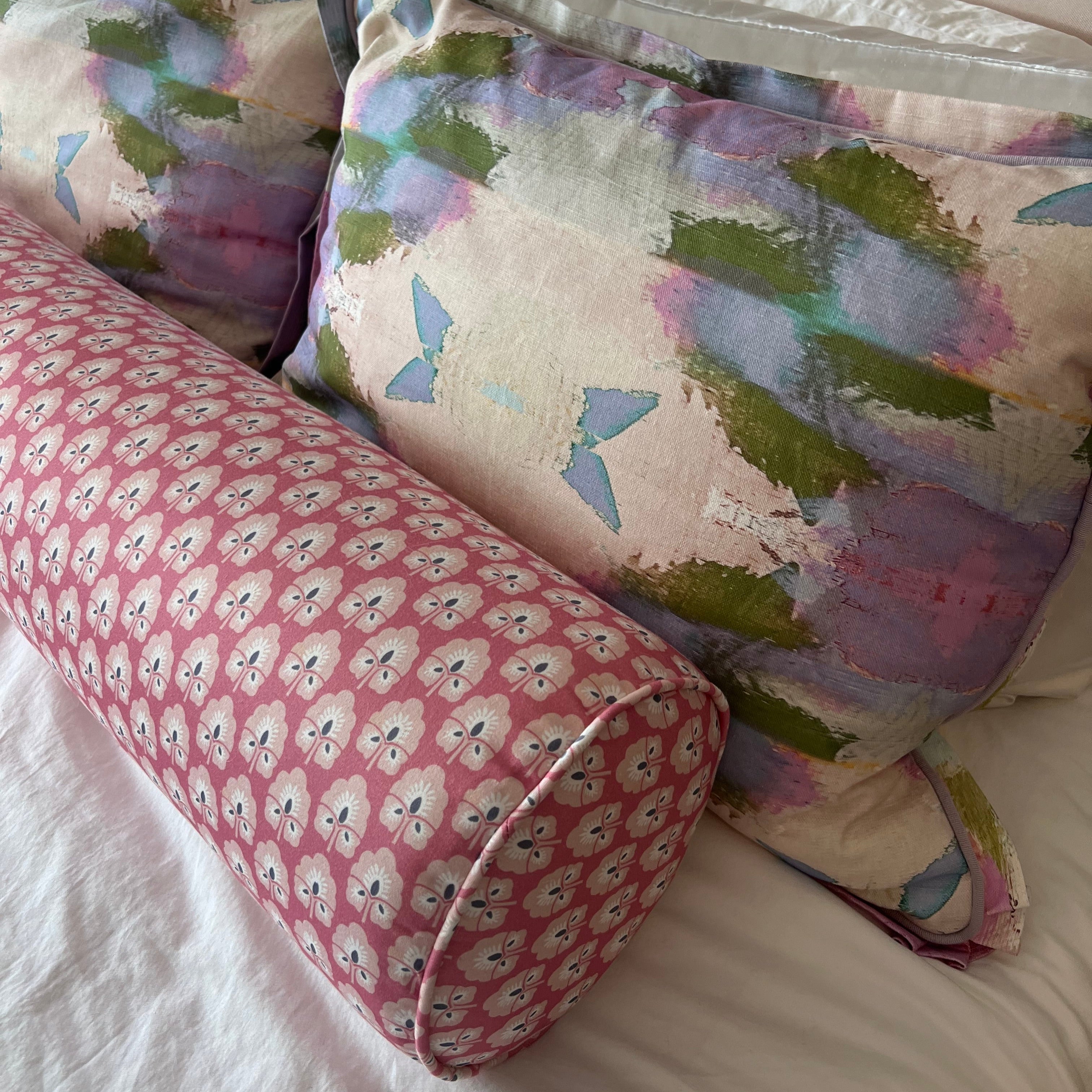 Decorative pillows with floral and butterfly patterns on a bed.