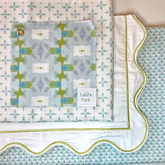 Baby blanket with geometric pattern and 'Laura Park' label on a matching quilt.