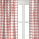 A coral colored drapery panel with a checkered pattern, displayed in a window setting.