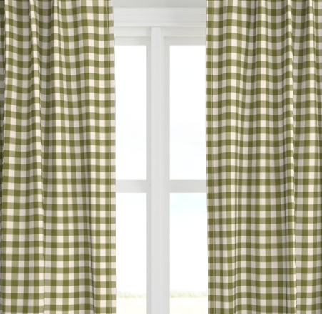 A set of green checkered drapery panels hanging on a window, with light entering through the window behind them.