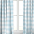 A set of blue drapery panels with a checkered pattern, hanging on a window.