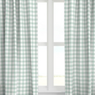 A set of seafoam green checkered drapery panels hanging on a window, with light filtering through the fabric.