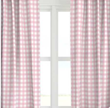A pair of pink checkered drapery panels hanging on a window, with the light from the window illuminating the room.