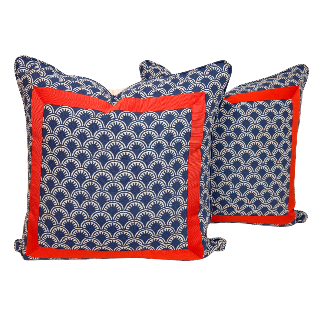 Two decorative throw pillows with a navy blue and white scallop pattern and a vibrant red border, displayed against a solid white background.
