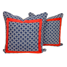 Two decorative throw pillows with a navy blue and white scallop pattern and a vibrant red border, displayed against a solid white background.