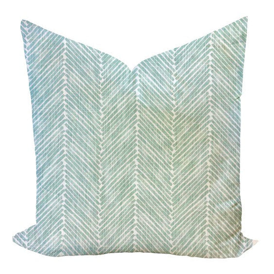 A decorative pillow cover with a geometric zigzag print in an aqua color, featuring a zipper closure.