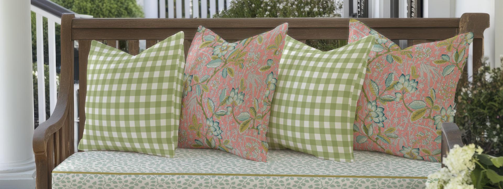 Decorative pillows on a wooden bench with a green and pink pattern