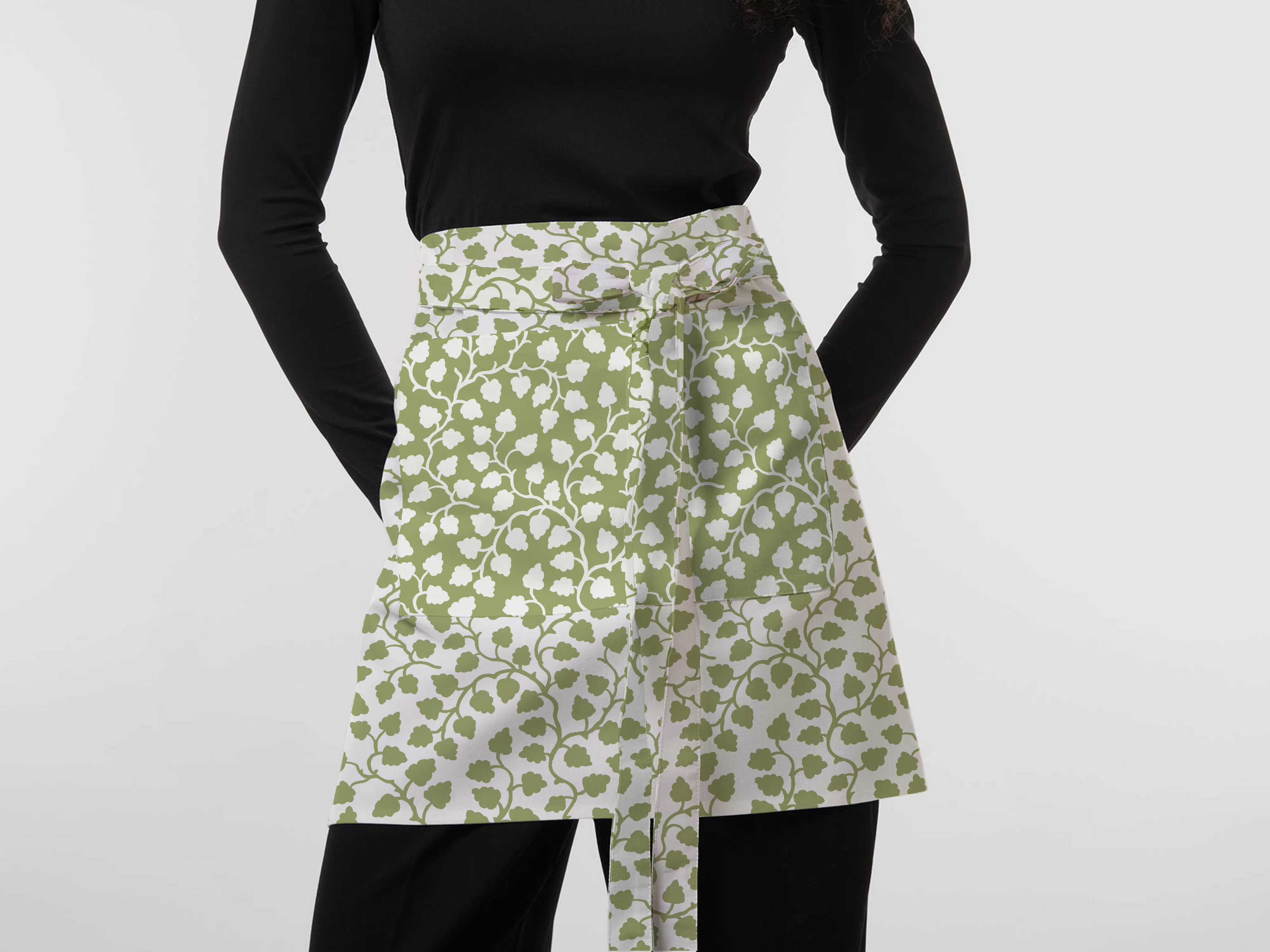 Woman wearing a green and white floral apron featuring exclusive Wheaton Whaley Home patterns and colorways.