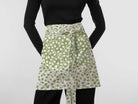 Woman wearing a green and white floral apron featuring exclusive Wheaton Whaley Home patterns and colorways.