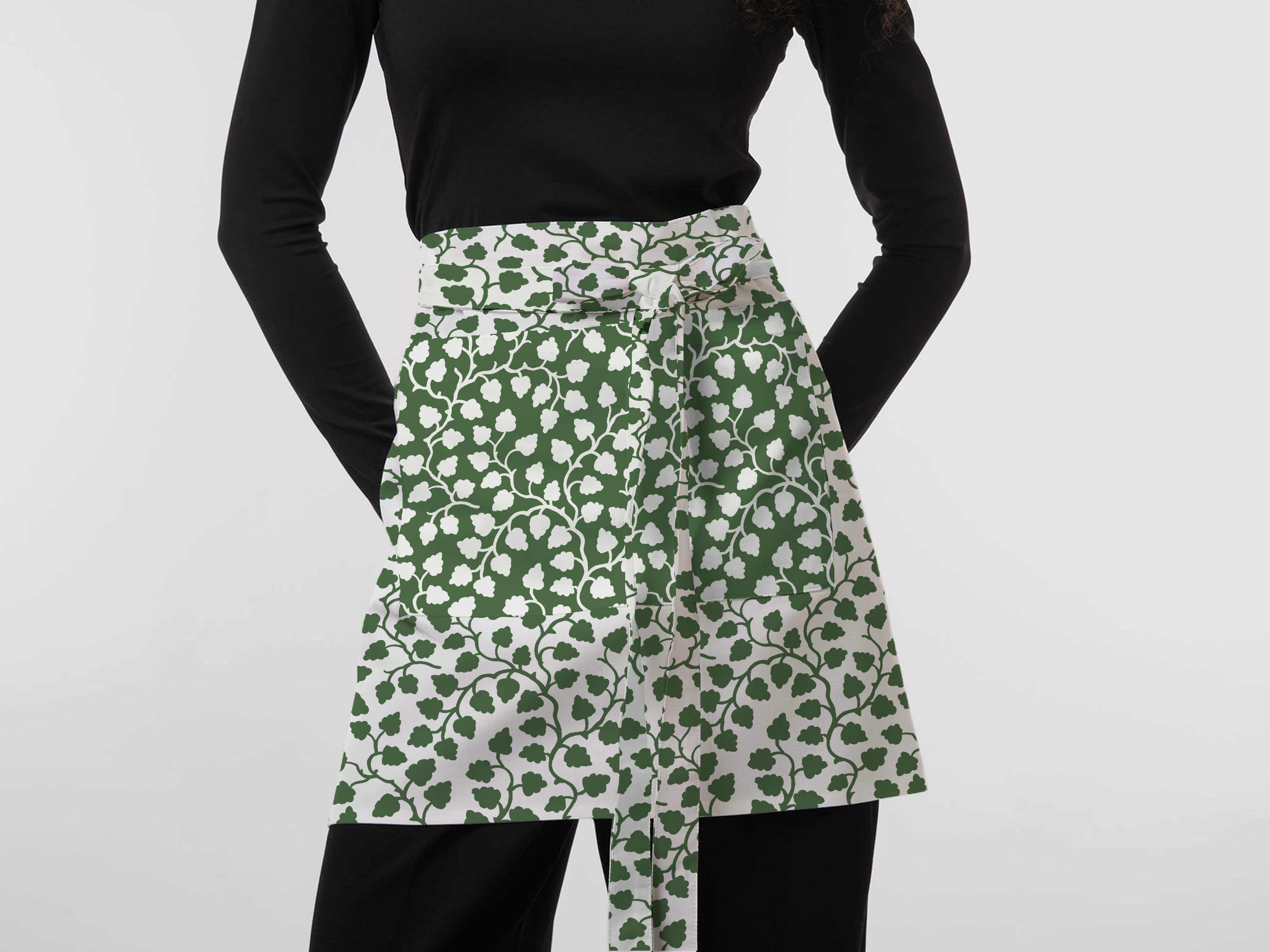 Woman wearing a green and white floral apron featuring exclusive Wheaton Whaley Home patterns and colorways.