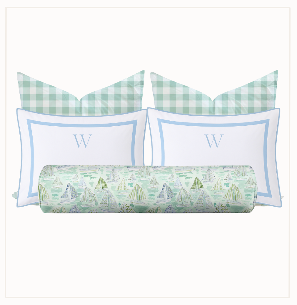 Set of pillows with green and white checkered patterns and a cylindrical pillow with sailboat design on a white background.
